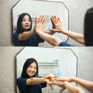 A woman smiling kindly at herself in the mirror, practicing self-compassion.